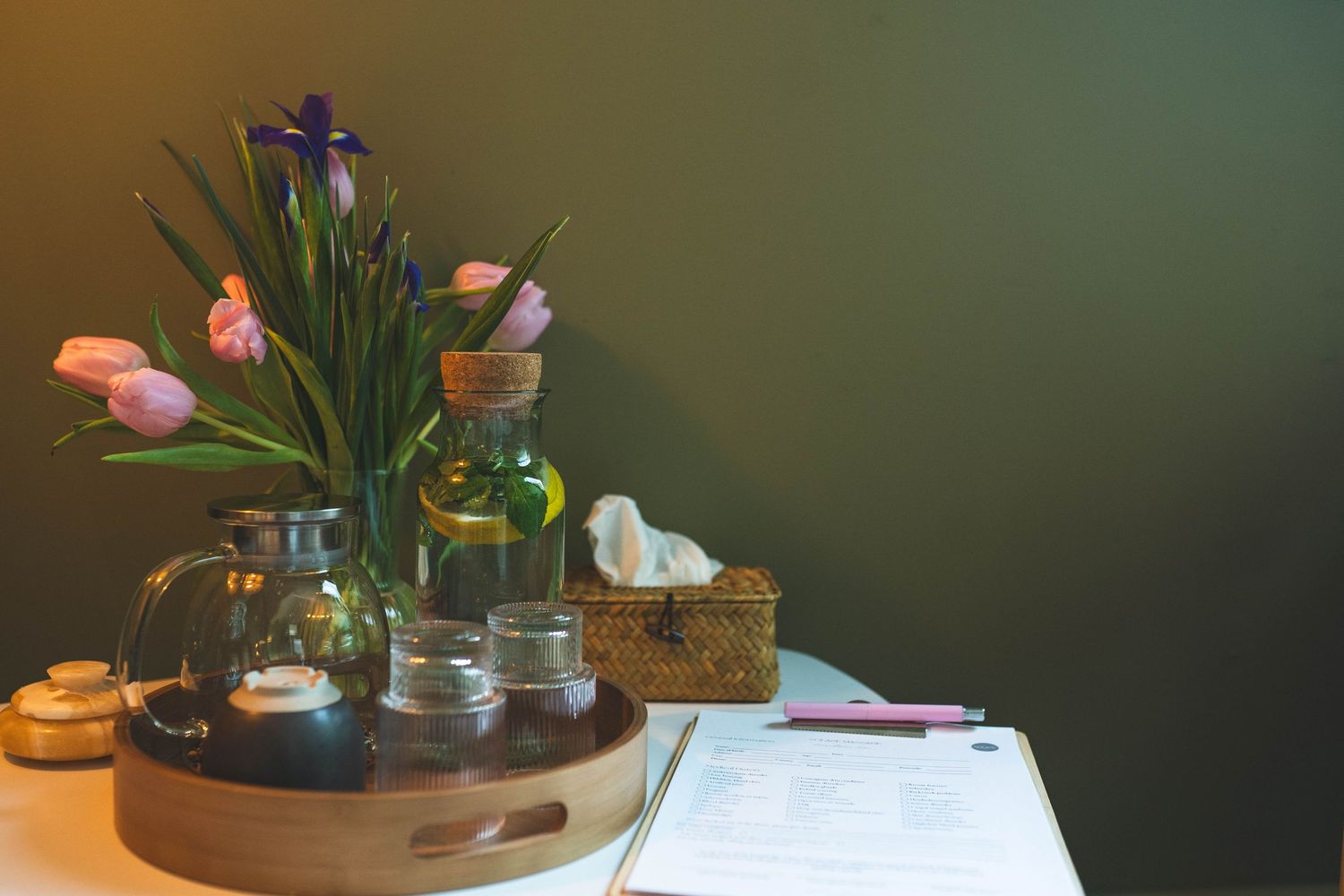 there is a table with glasses on a tray and a vase of flowers