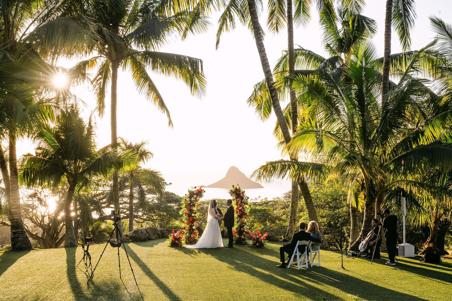 Palm trees sway against a golden sunset sky at a tropical beach resort creating a serene paradise atmosphere.