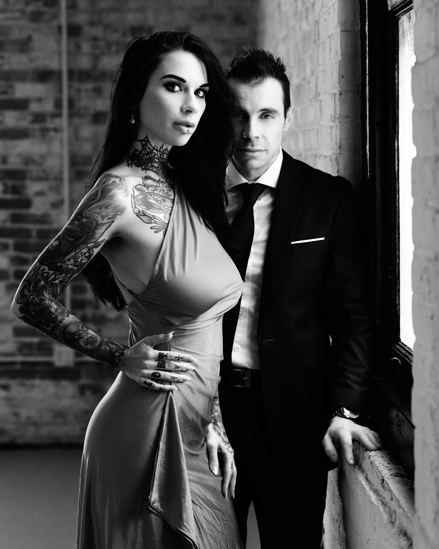 David G Holt Photography - Black and white portrait series showing couple in elegant attire posing against brick wall.