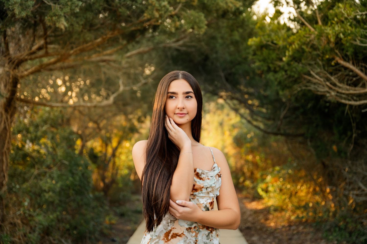 Outdoor portrait session in golden sunlight with natural foliage backdrop.