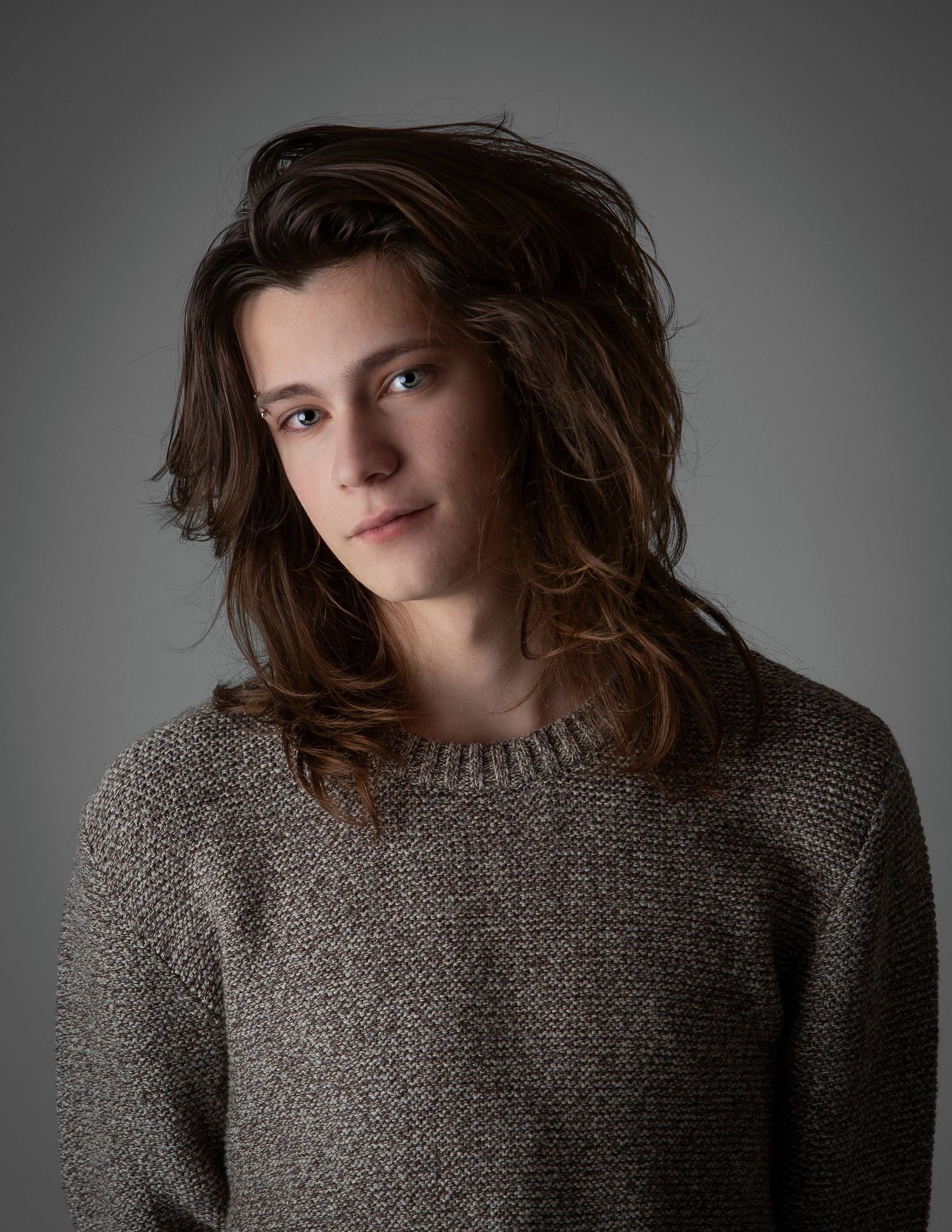Moody portrait series showing someone in a gray sweater against dark background with dramatic lighting and tousled hair.