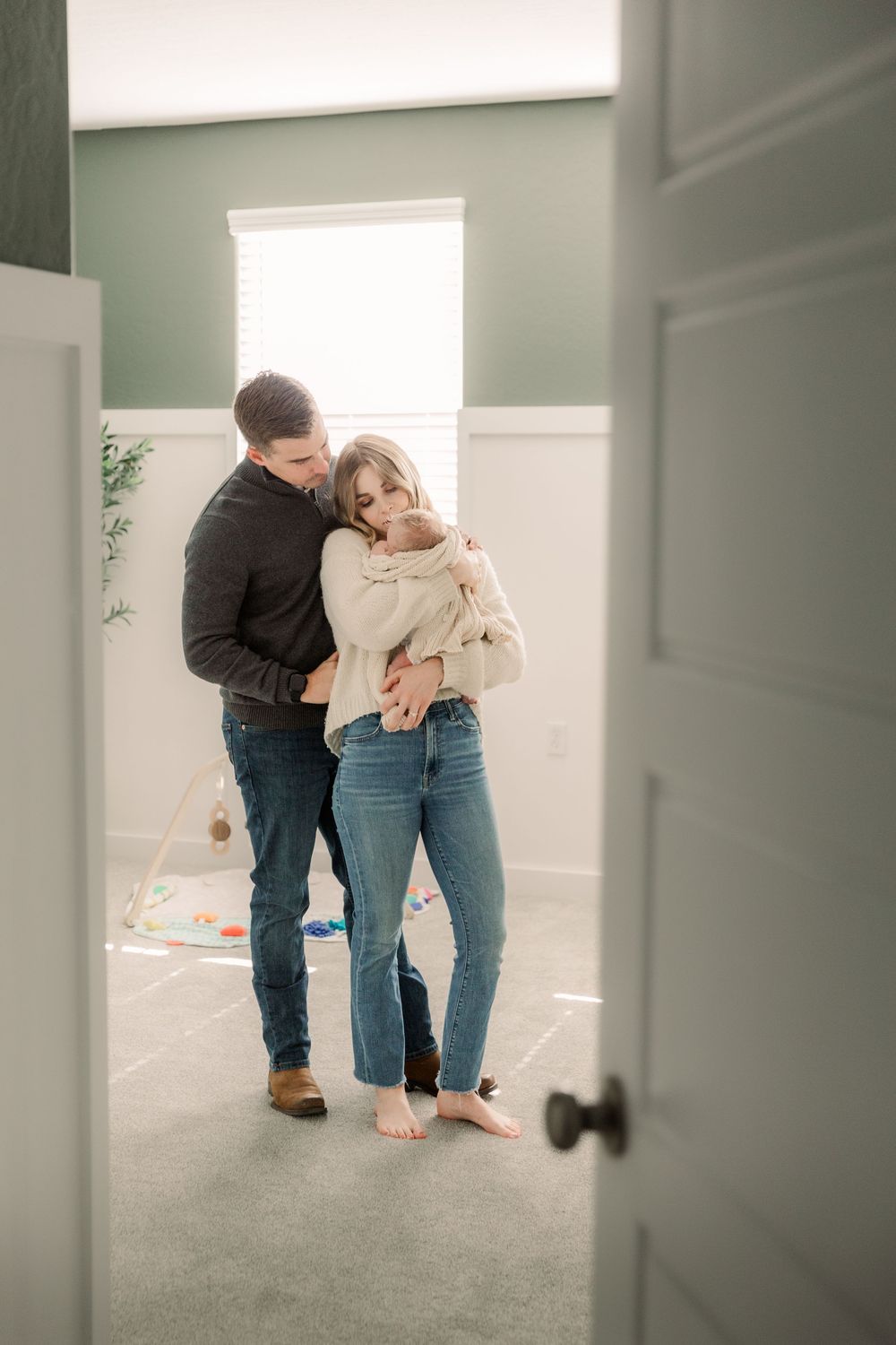 Intimate view through doorway of couple embracing in casual attire in a sunlit room.
