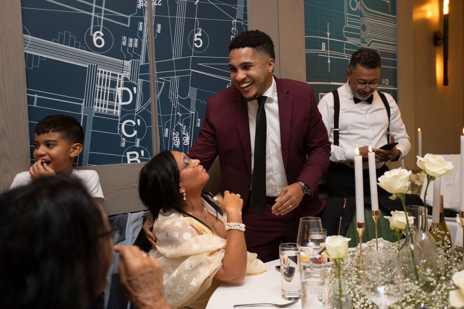 A group of well-dressed guests enjoy a formal dinner party with wine glasses and elegant table settings.