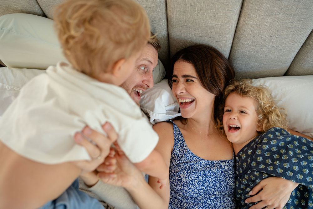 Candid family photos showing natural laughter and play during an intimate home photoshoot.