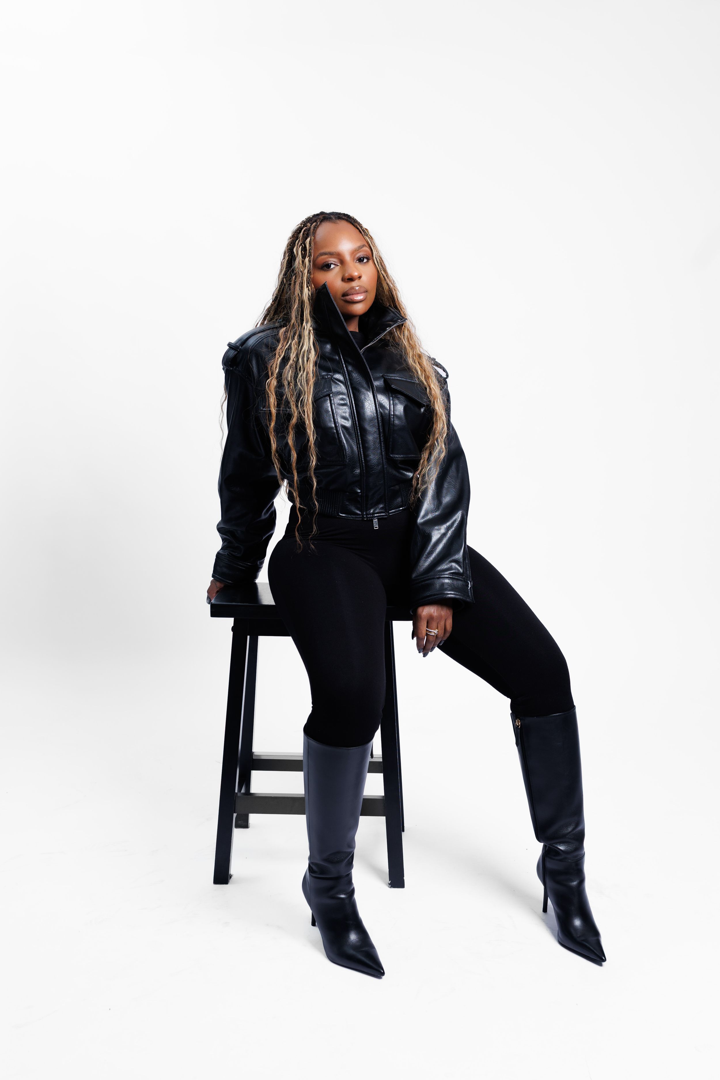 Person in black leather outfit poses expressively on dark chair against white background in three different positions.