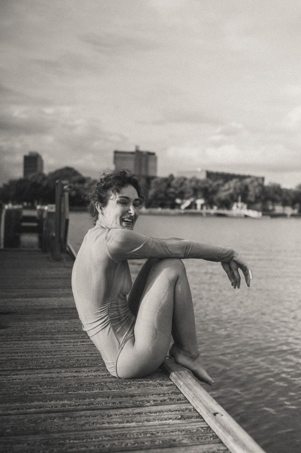A black and white sequence of photos showing a person lounging on a wooden dock by the water on a cloudy day.