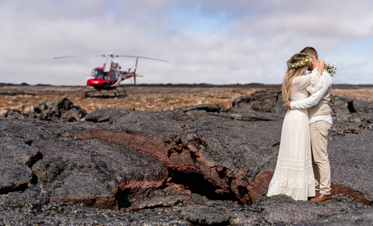 Couple embracing with helicopter in the background at Reykjanes eruption site, Iceland