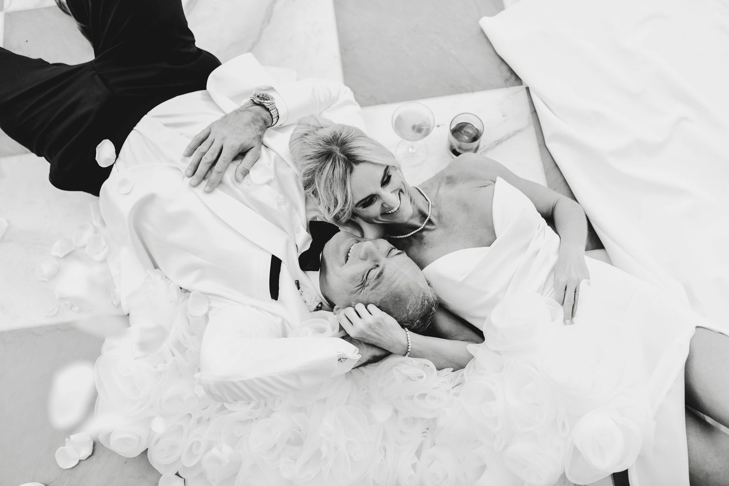 Romantic wedding photo of a couple laying together on a black and white floor