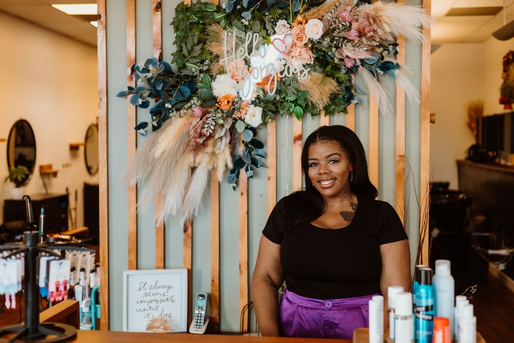 A beauty salon interior features a wooden slat wall decorated with elegant floral arrangements in pink and white.