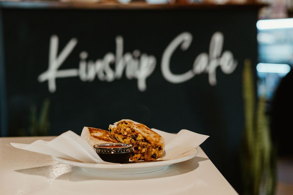 A rustic wooden table displays fresh baked goods and pastries in a cozy cafe setting.