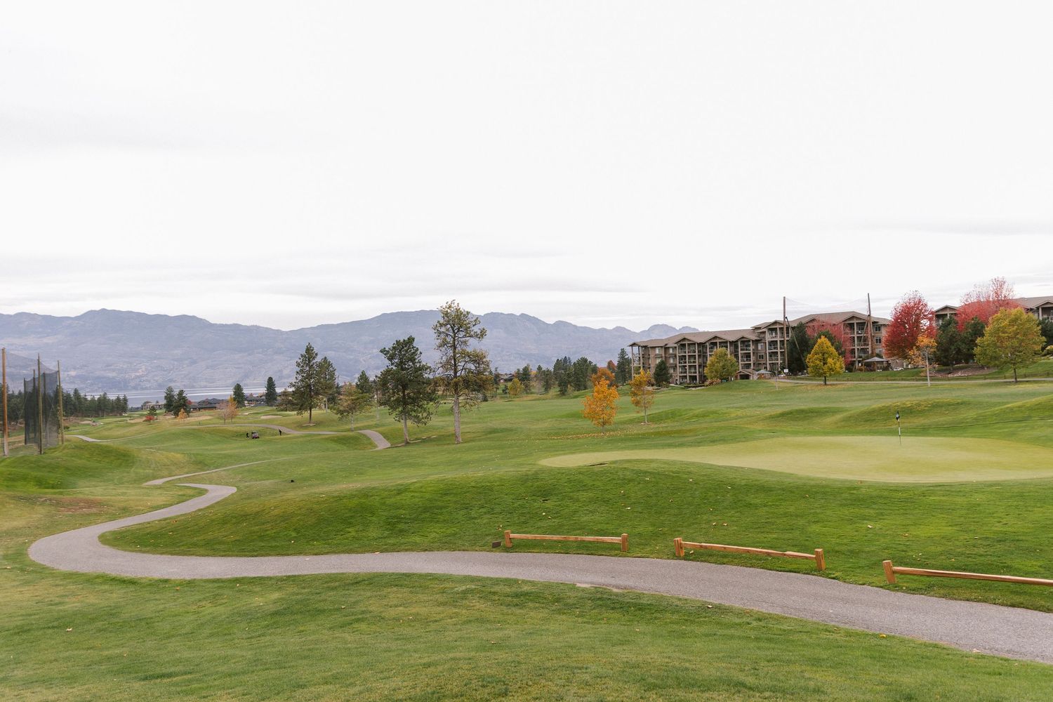 Rolling green hills and mountains create a scenic landscape with autumn trees and winding paths.