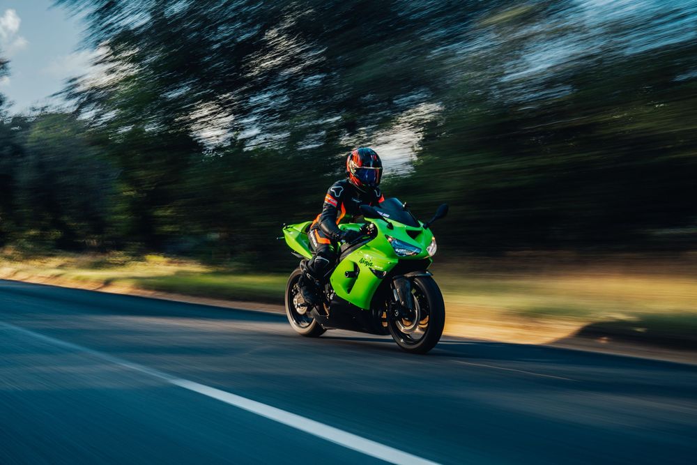 Dynamic shot of motorcycle rider leaning into turn on winding road with dramatic motion blur.