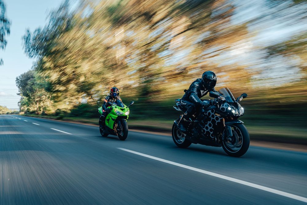 Motorcycle racing through a tree-lined road with motion blur showing high-speed movement.
