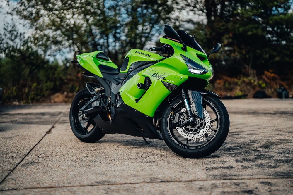 A bright green Kawasaki Ninja motorcycle parked on a concrete surface showcases its sleek profile and sporty design.