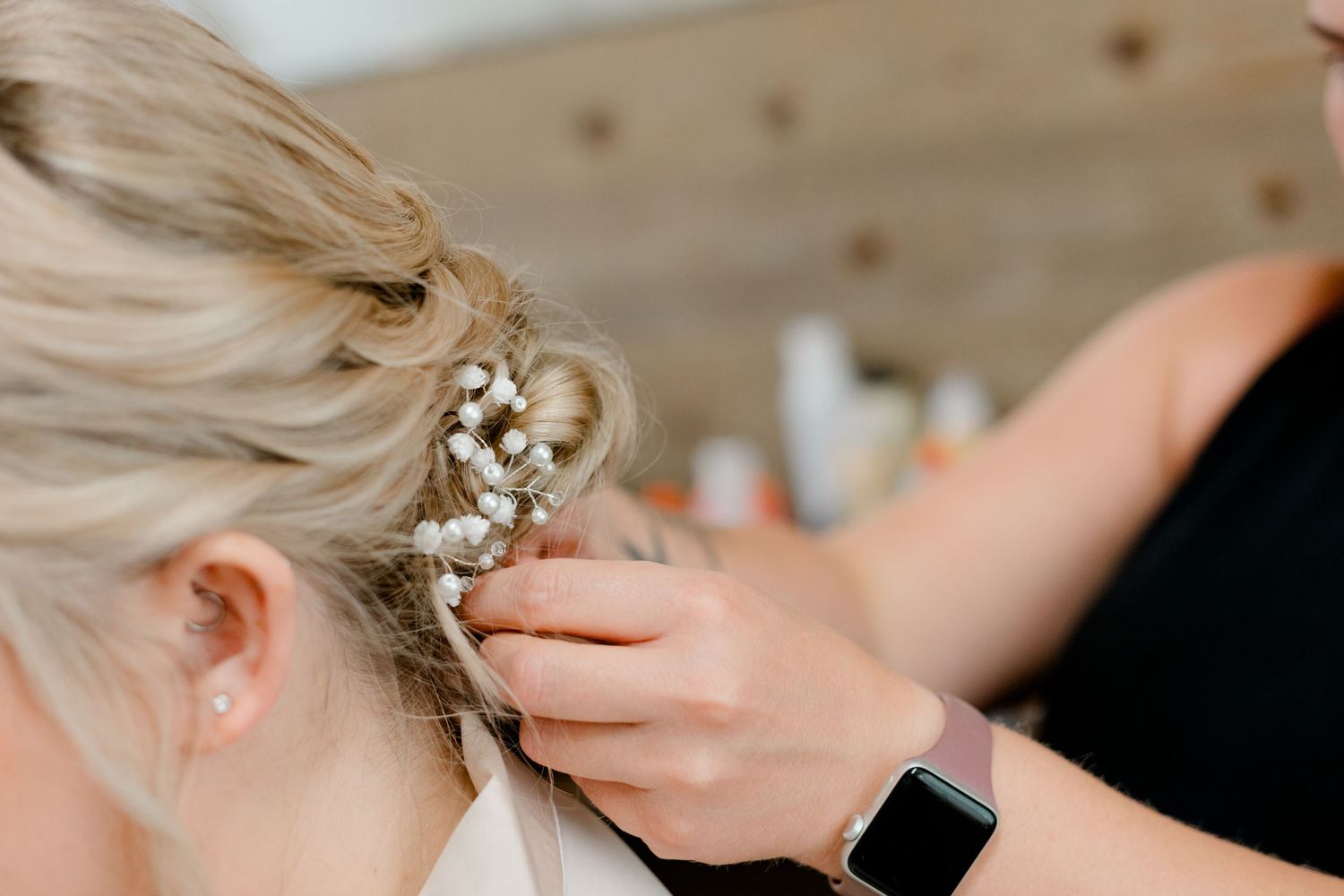 Hairstylist adding pearl floral hair accessories to an elegant bridal updo.