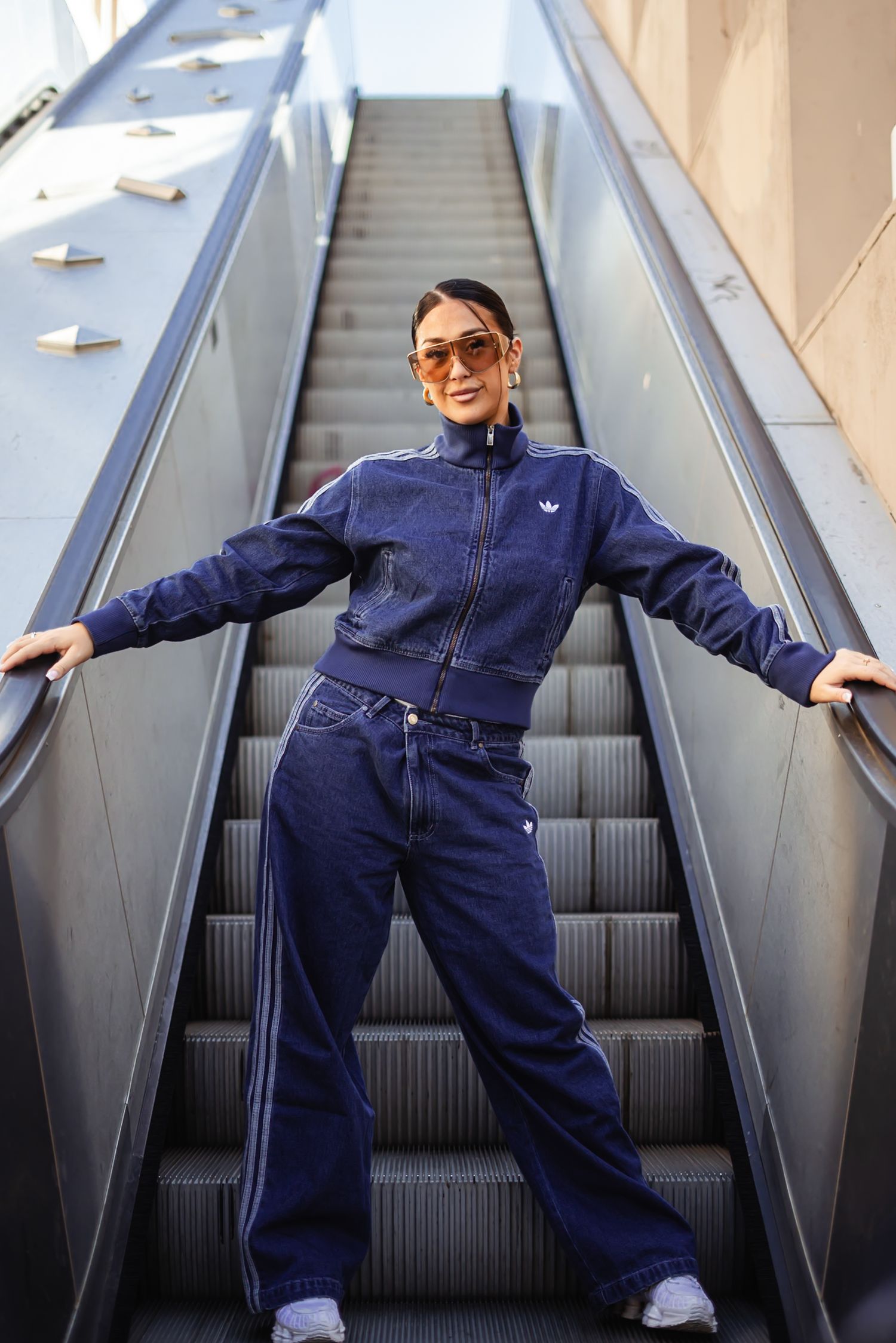 Person in navy blue tracksuit performs playful poses on escalator in sequence of connected photos.