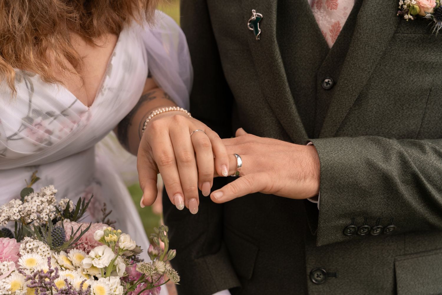 Hands of a bride and groom cutting their white wedding cake together at an elegant reception.