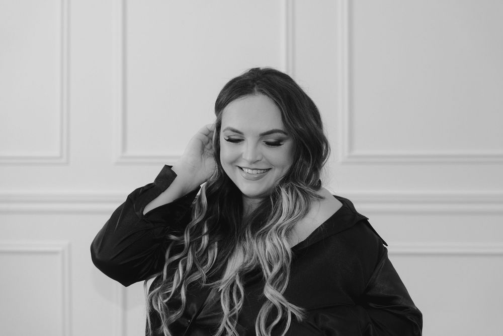 Woman in black sweater poses in multiple casual shots against white wall background.