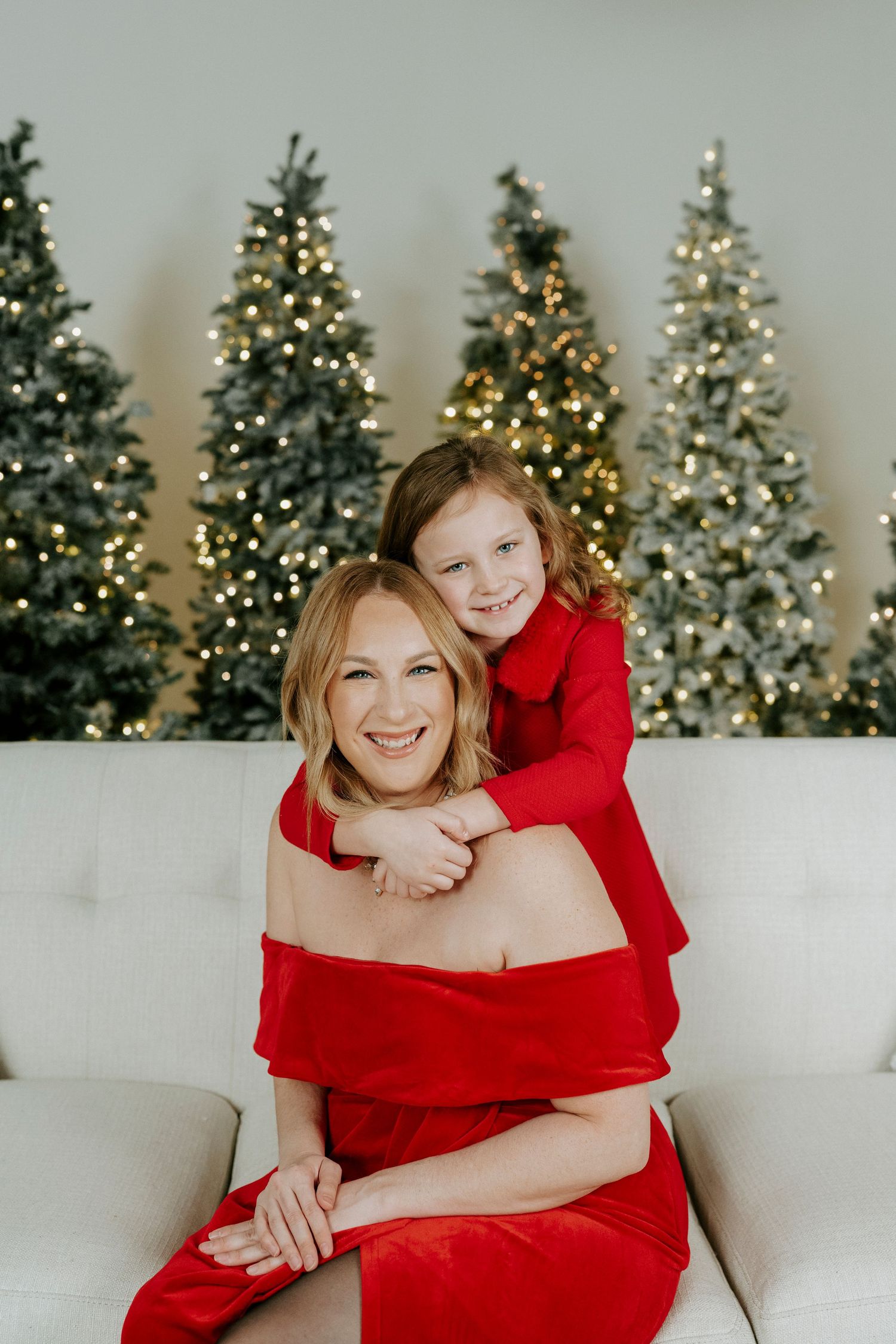 Holiday portraits with red dresses against a backdrop of illuminated Christmas trees create a festive winter scene.