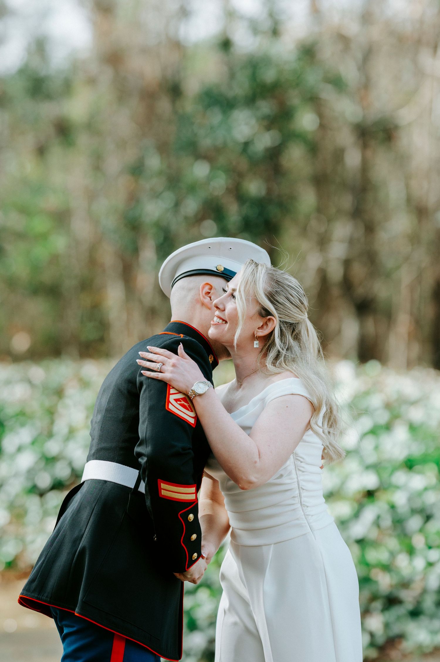 A romantic wedding moment captured outdoors with a military service member and bride sharing a tender embrace.