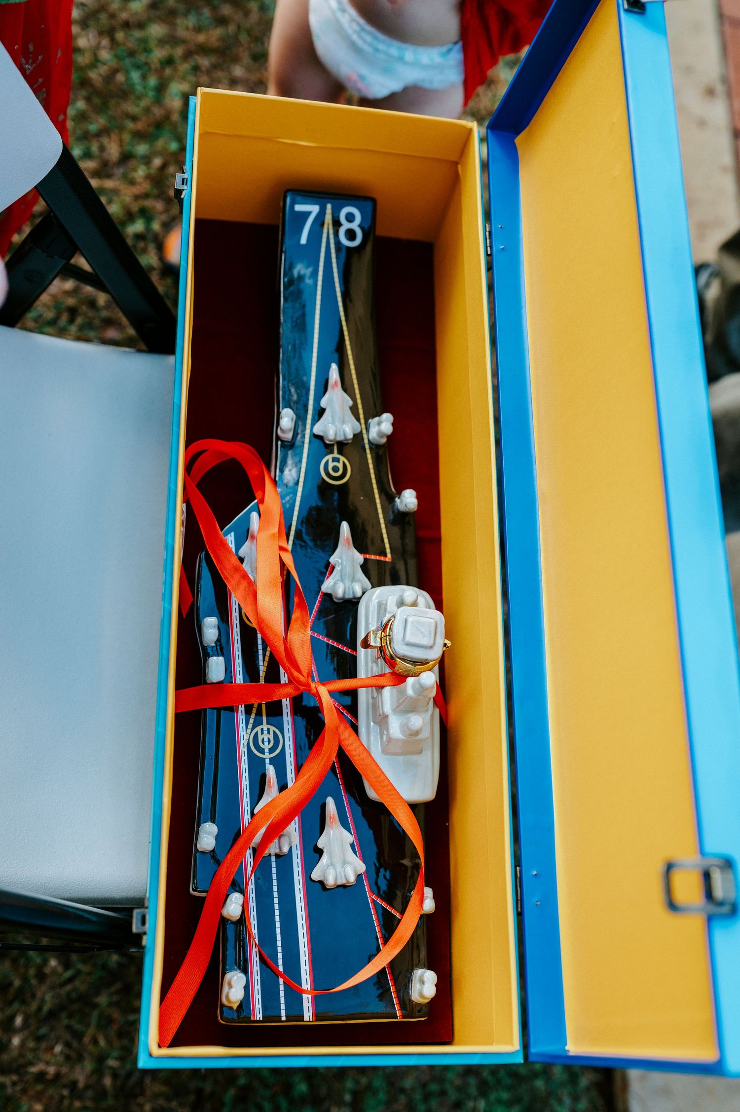 Open blue and yellow box containing skis with orange straps and equipment marked with number 78.