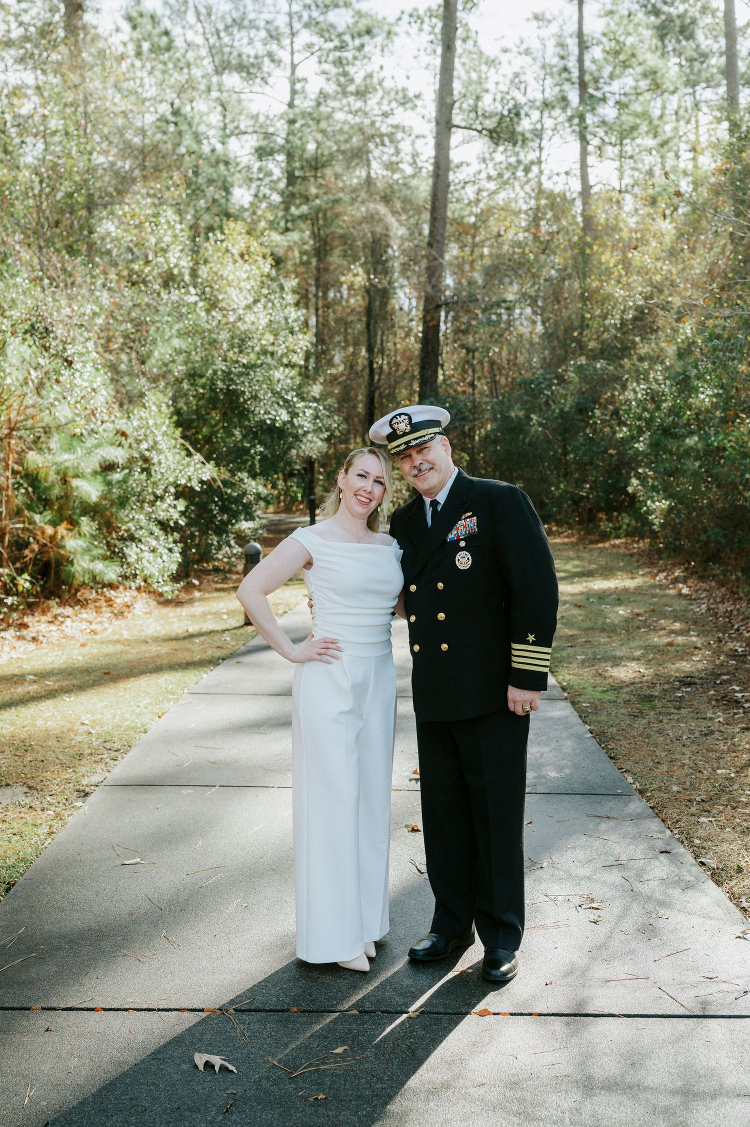 A couple poses together on a winding path surrounded by trees on their wedding day.