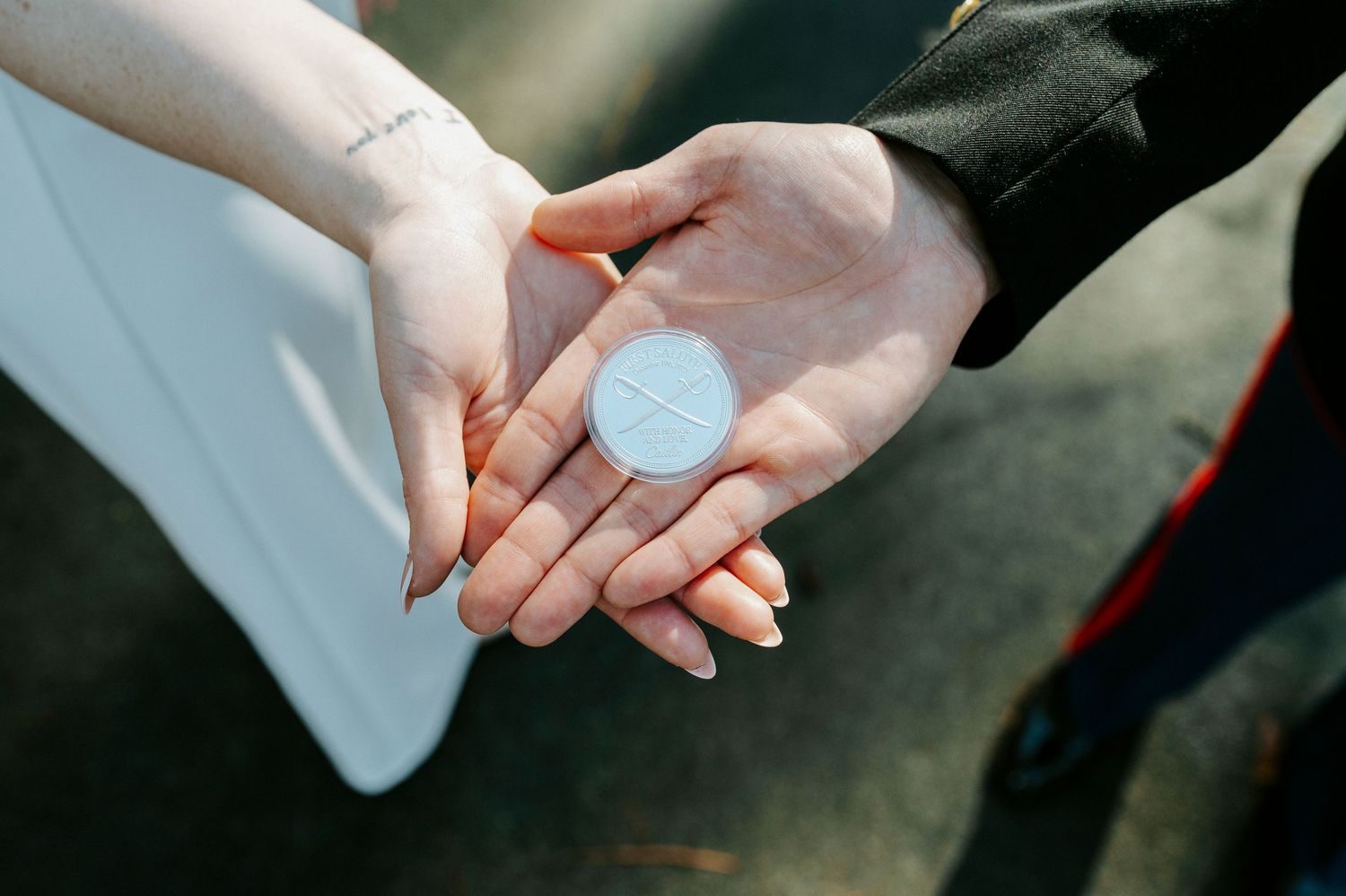 Two hands exchanging a small light blue round object in natural daylight.