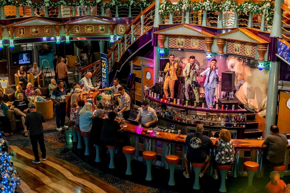 Colorful nighttime bar scene with neon lights and patrons gathered at a busy outdoor venue.