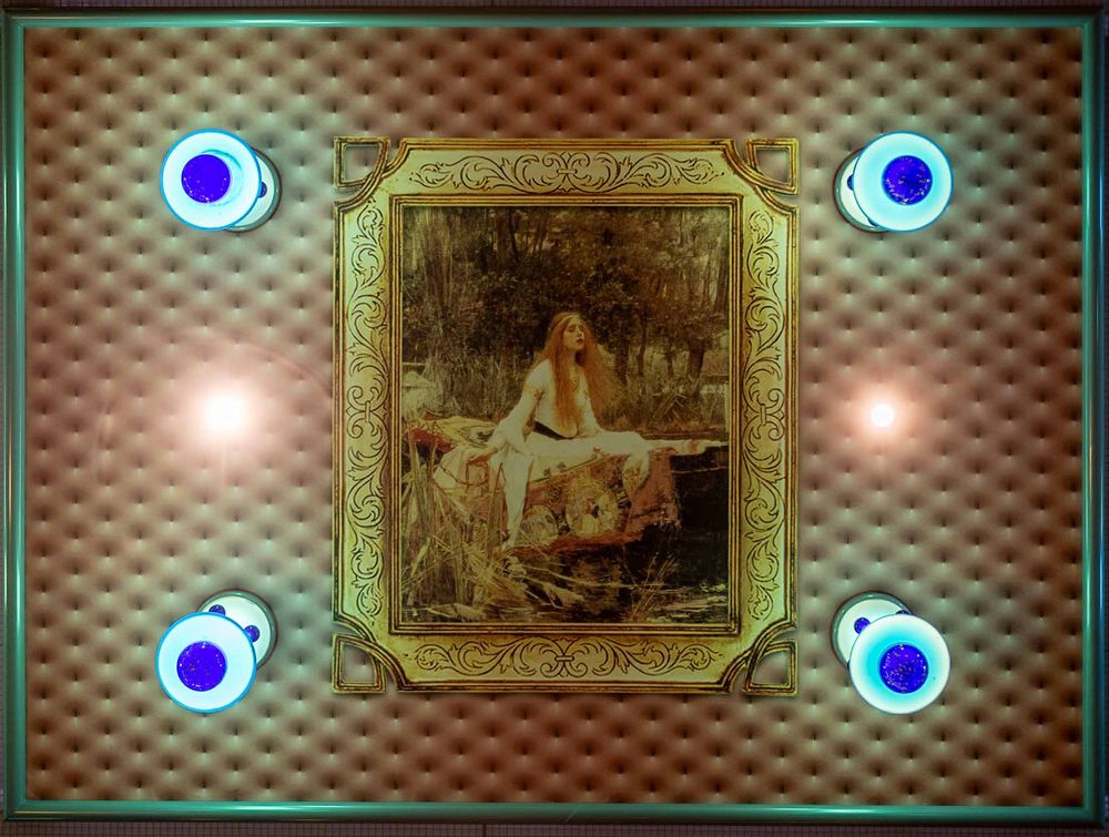 Vintage artwork in ornate gold frame mounted on textured wall with four glowing blue LED lights at the corners.
