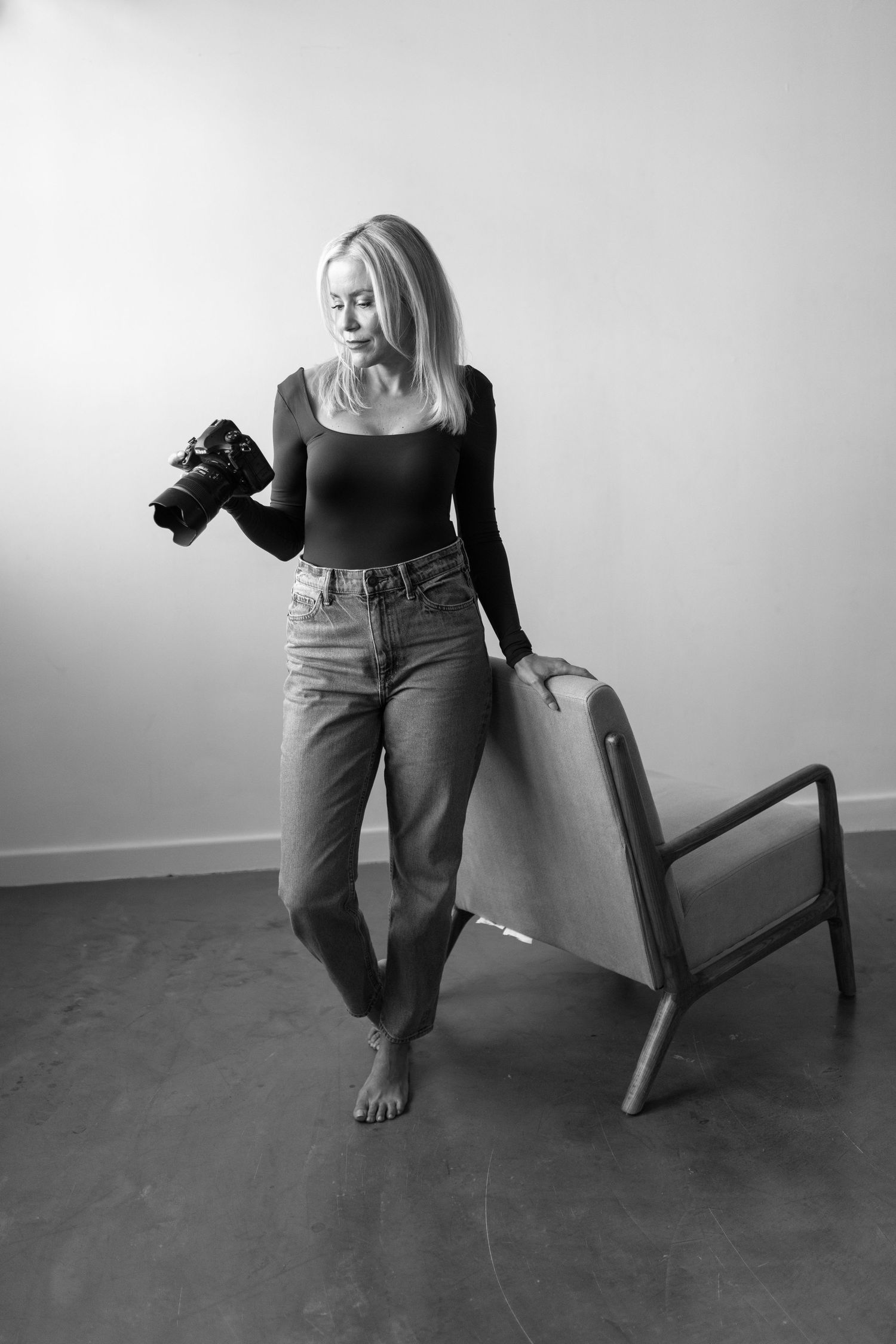 A relaxed person in blue jeans and gray sweater sits comfortably on a couch while holding a warm beverage.