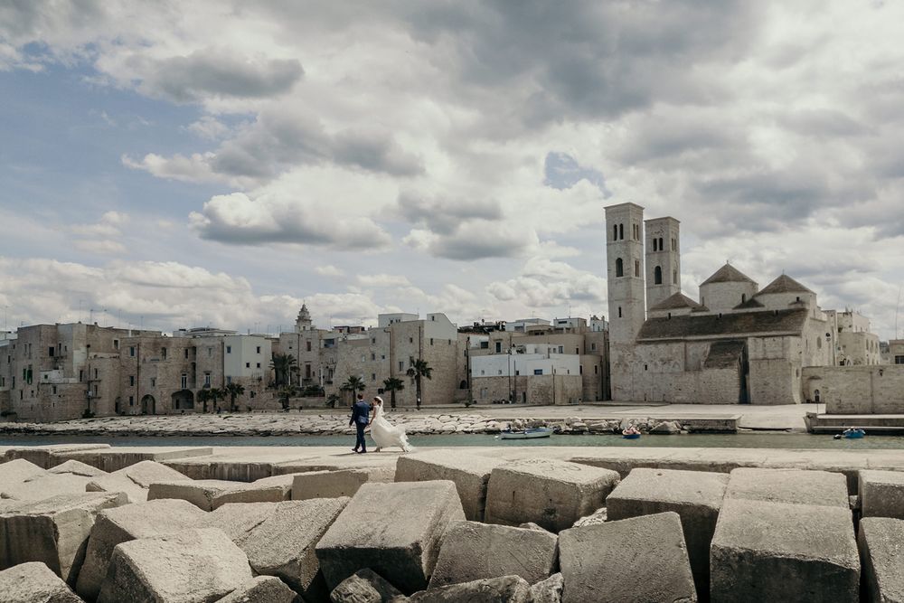 Panoramic view of a coastal town with white buildings and dramatic cloudy sky over the Mediterranean.