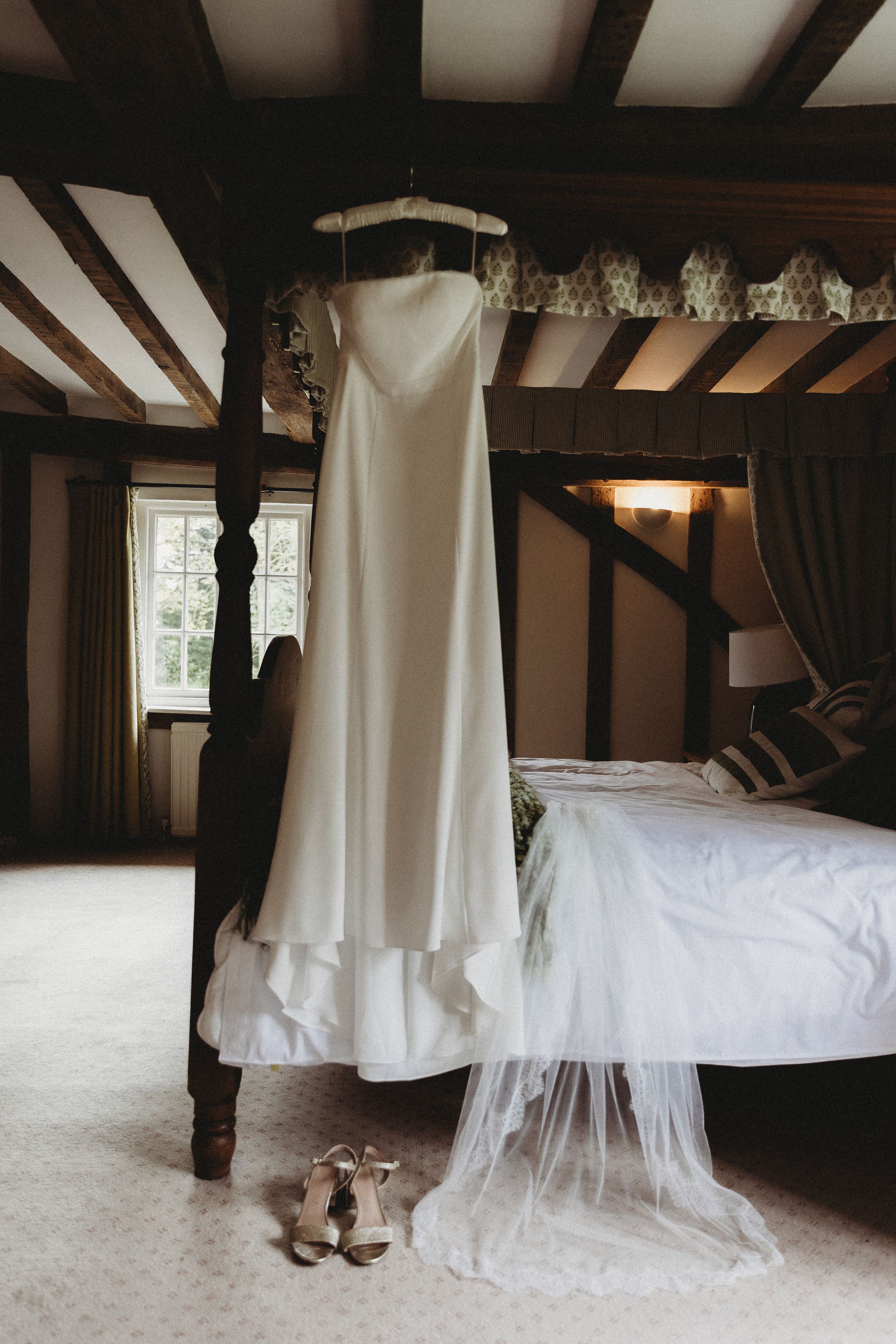 Brides dress hanging from four post bed at Henham Park