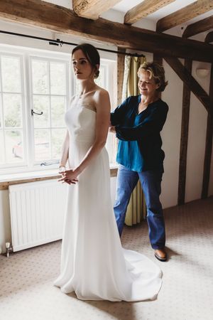 Mother of the Bride helping Bride with dress at Henham Park