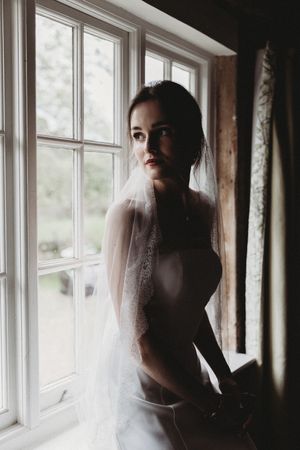 Bridal portrait of bride looking out of window at Henham Barns
