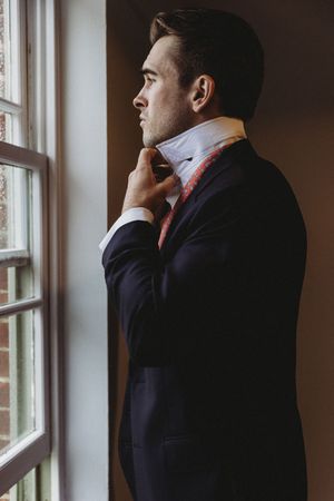 Groom making final adjustments to tie at Henham Barns