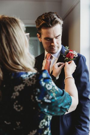 Mother of the Groom adjusting Groom's button hole at Henham Weddings