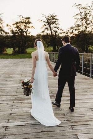 Candid photo of bride and groom walking across bridge at Henham Park Weddings