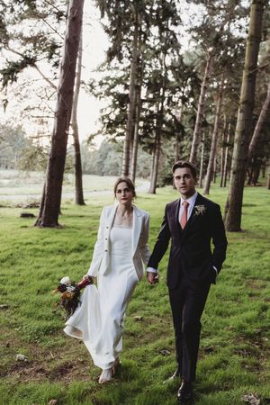 Bride and Groom holding hands in the woods at Henham Barns