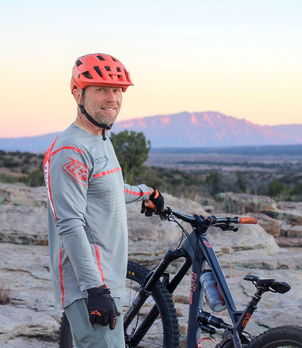 Portrait of man with mountain bike in at sunset in front of the Sandia Mountains.