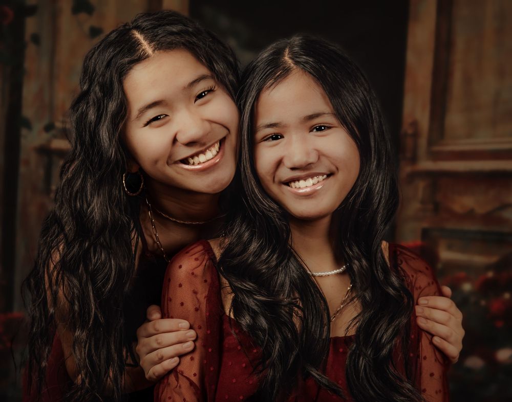 Two people in red lace dresses pose together for a series of warm, candid portraits.