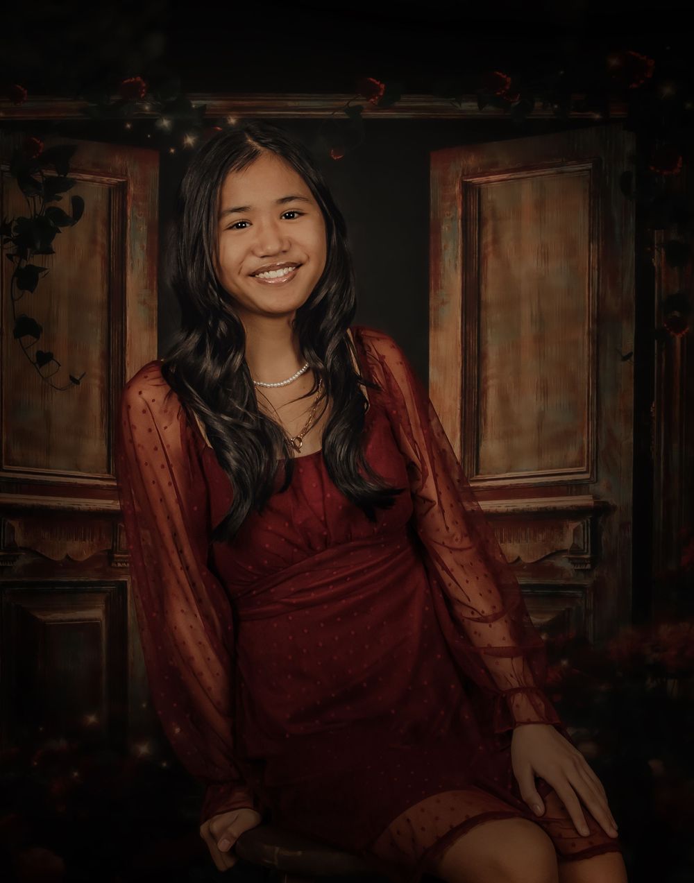 A person in a burgundy dress poses in a dimly lit room with wooden paneling creating a moody atmosphere.