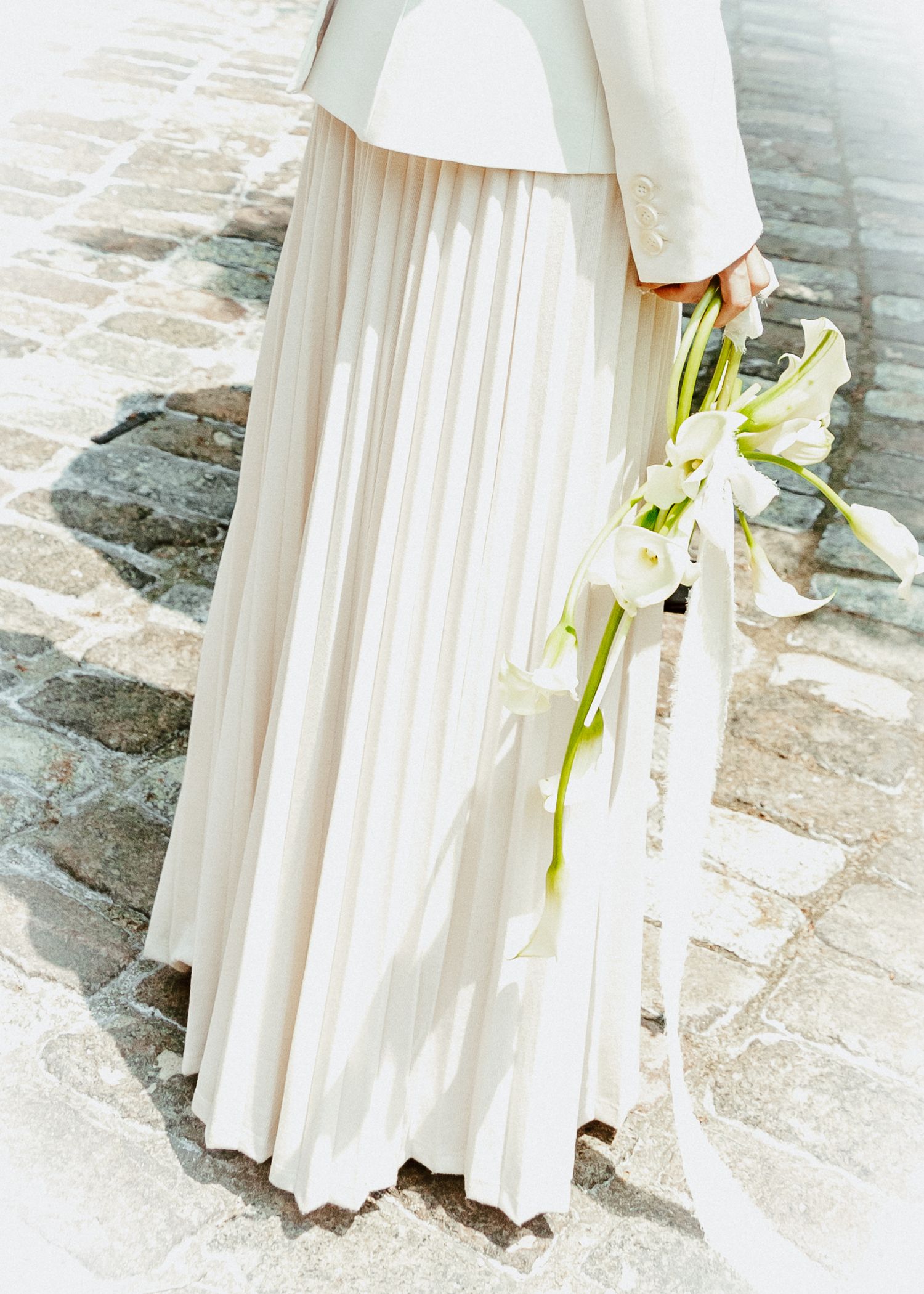 Flowing white dress details against stone steps in an elegant setting.