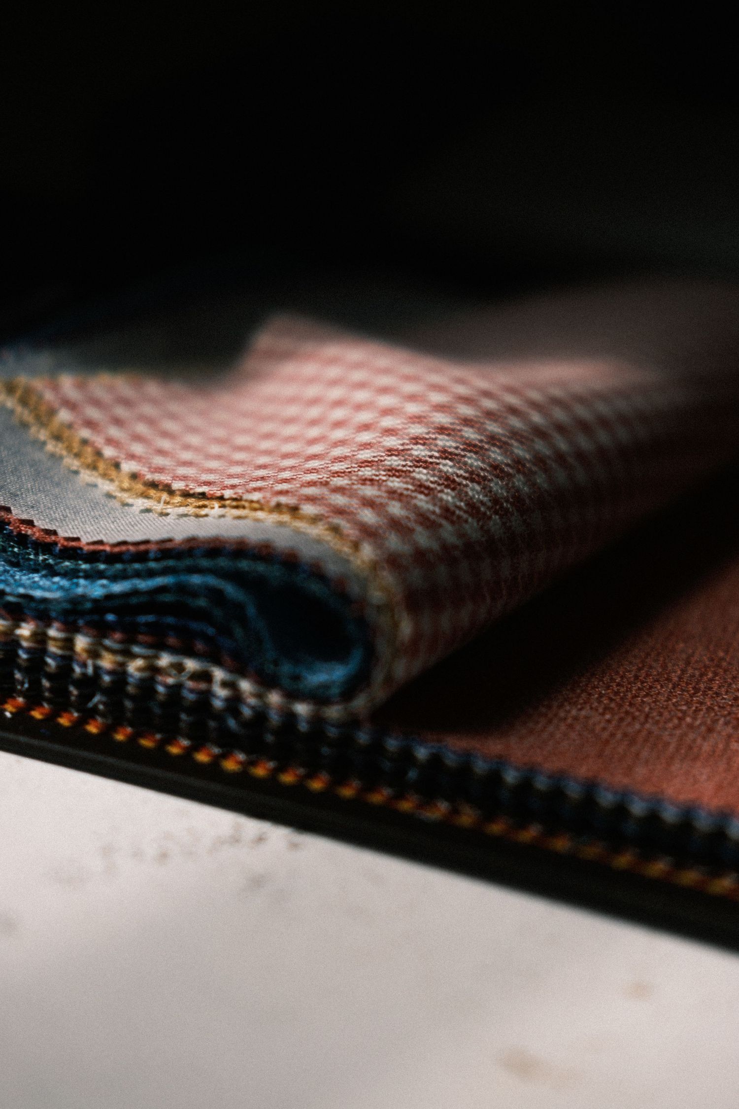 Close-up macro shot of folded fabric with checkered pattern in pink and blue tones showing detailed textile texture.