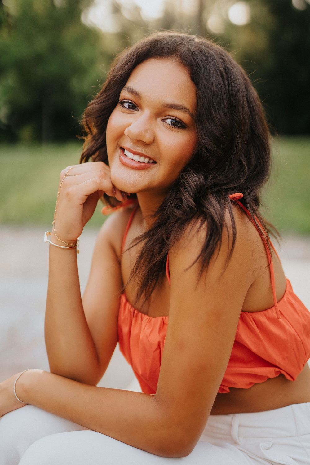 A series of outdoor portrait photos showing someone in a coral-colored top laying on a white surface in natural lighting.