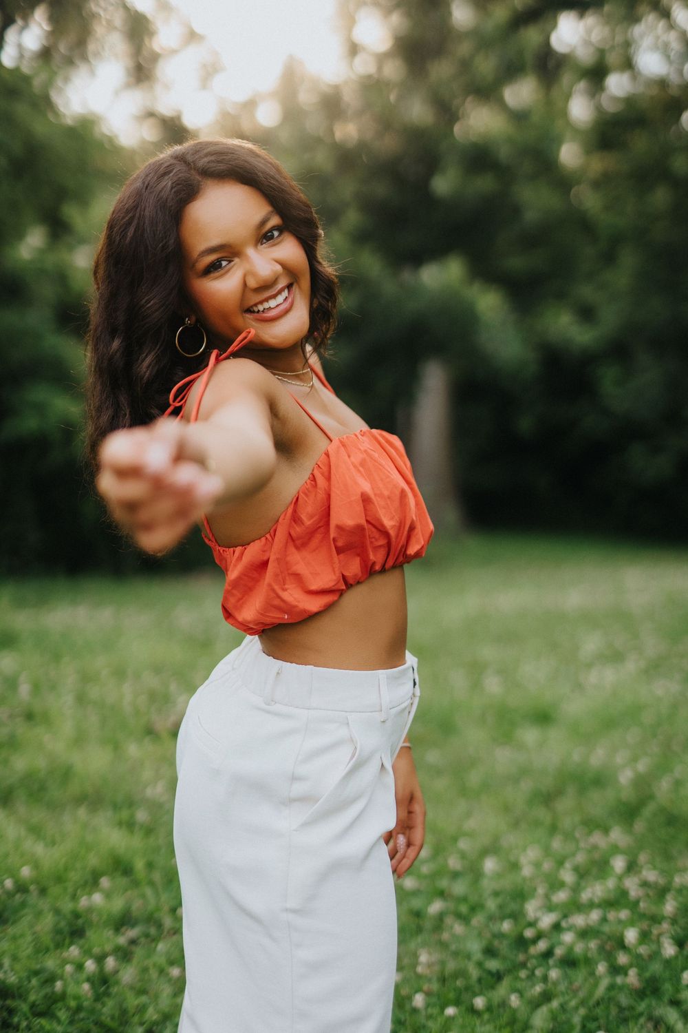 A series of outdoor portraits showing joyful expressions in an orange and white outfit against a natural green background.