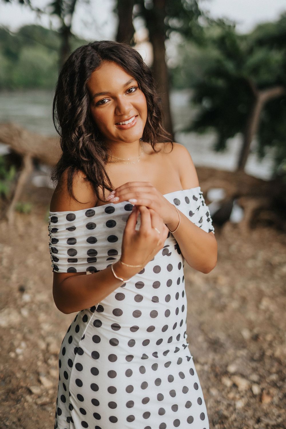 A playful photoshoot featuring a polka dot dress against a natural outdoor setting.