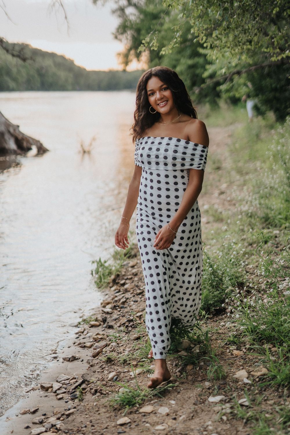 A polka dot dress stands out against the natural shoreline backdrop during an outdoor photoshoot.