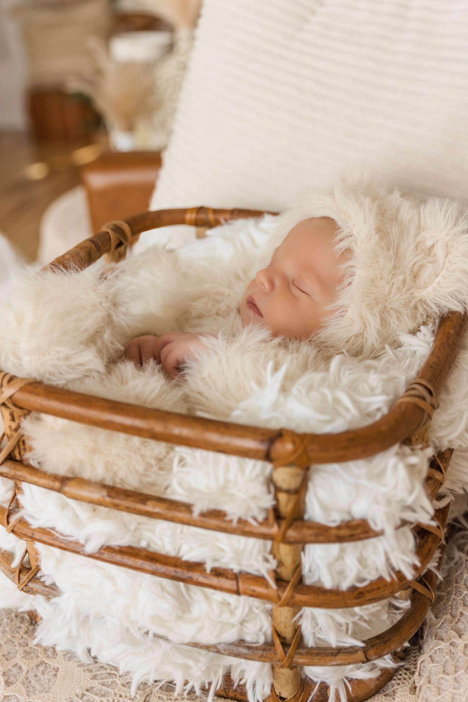 Newborn sleeping peacefully on vintage wooden bed with white fluffy fur blanket.