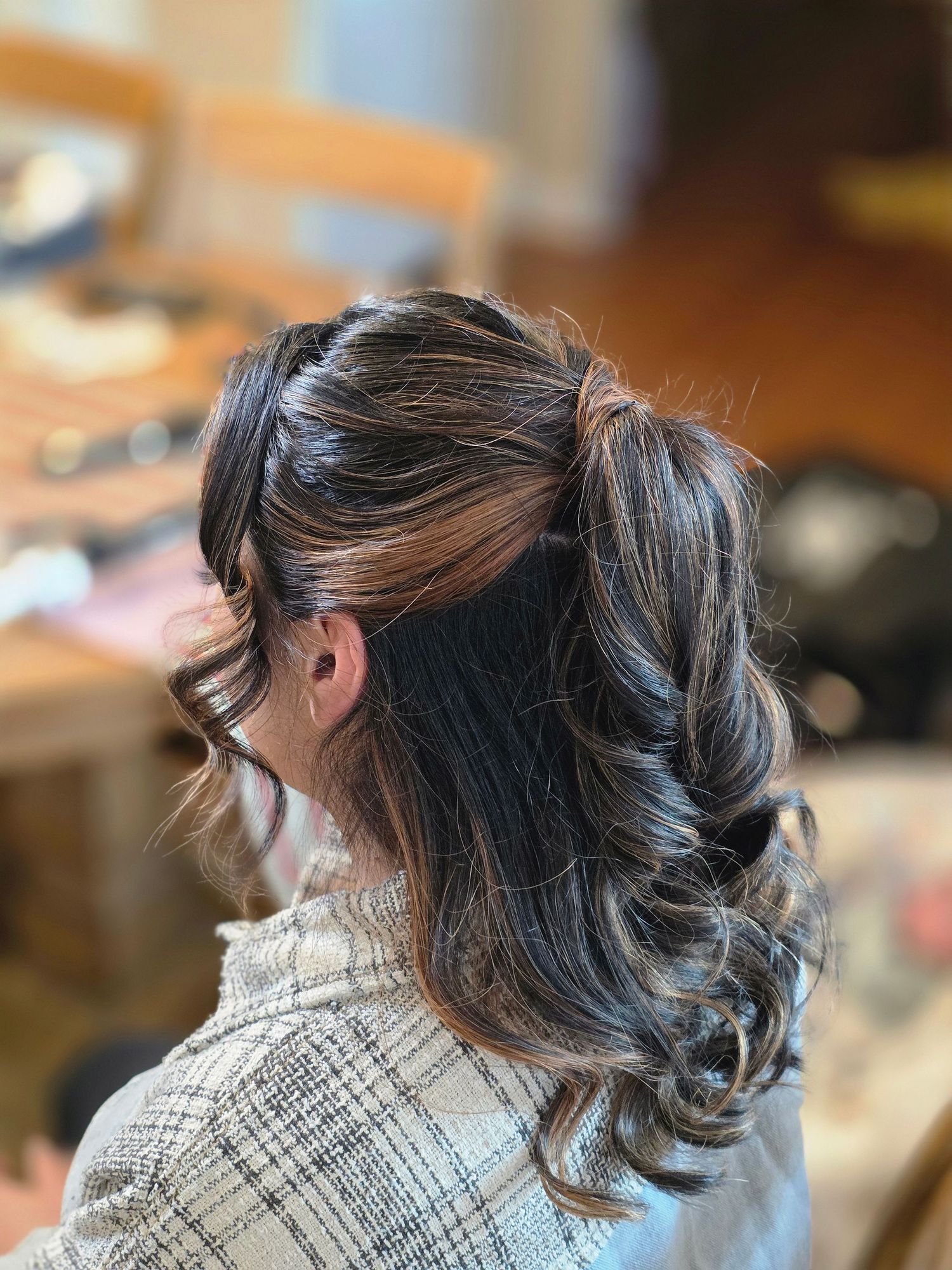 Profile views showing dark hair in sleek updo with glasses and black jacket.