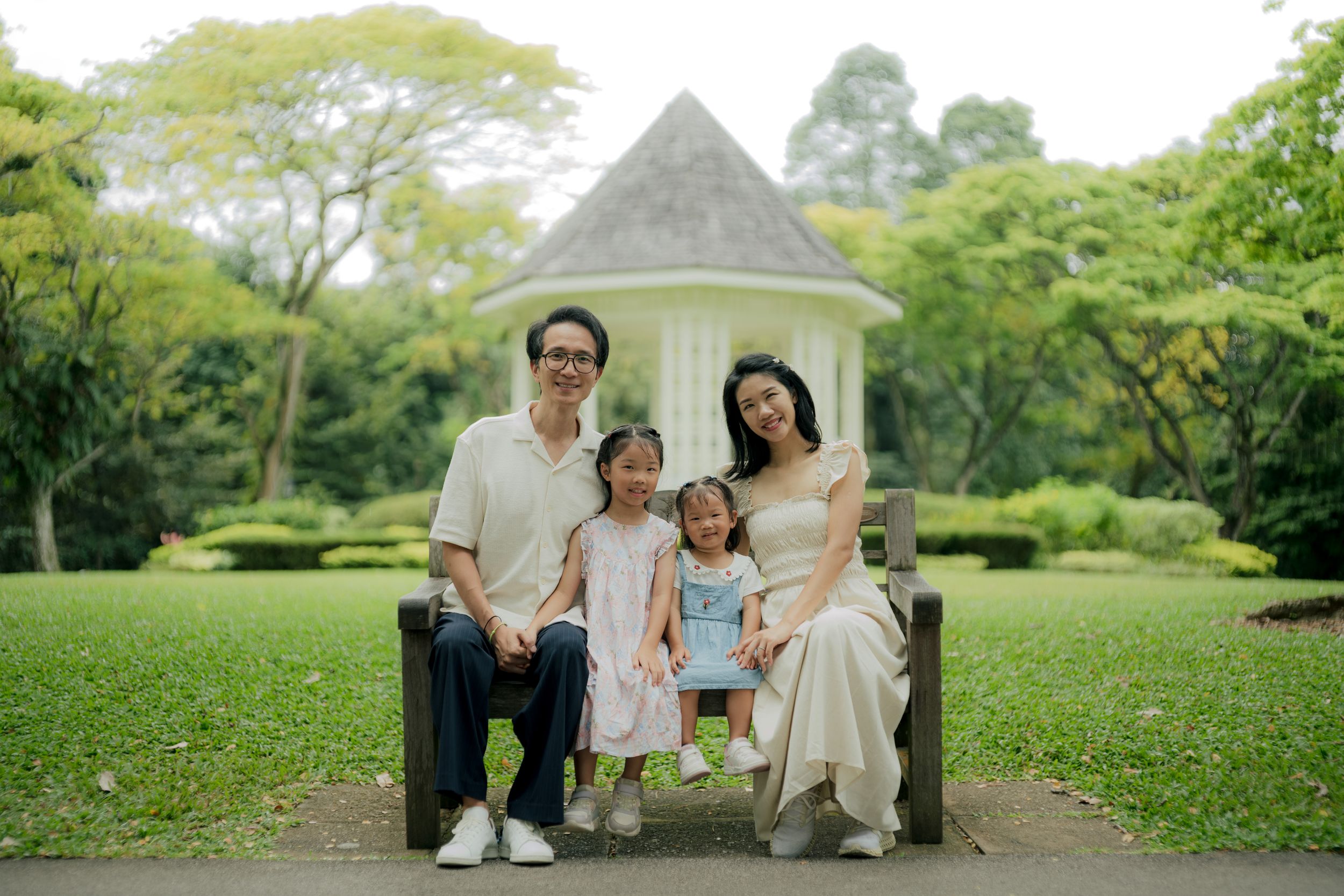 Family portrait session in an elegant garden setting with white gazebo and green landscaping.